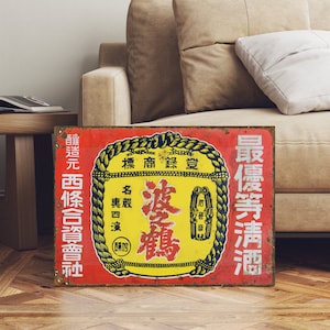 以下が含まれることがあります： 「波鶴」 (ハツル) 酒のレトロな錆びた金属製の看板。「最優等清酒」 (サイユウトクセイシュ) と書かれており、これは「最高級の日本酒」を意味します。「醸造元 西條合資會社」 (ジョウゾウゲン サイジョウゴシカイシャ) は、「醸造元 西條合資會社」を意味します。看板は赤色で、黄色と黒色の文字が書かれており、鶴のスタイリッシュな絵が描かれています。