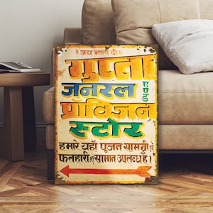 May include: A vintage-style metal sign with faded paint advertising a general store called "Gupta General Provision Store". The sign is yellow, green, blue, and red with Hindi text that reads "Jai Mata Di" and "Hamari yaha poojan samgri & falhari ka saman uplabdh hai".