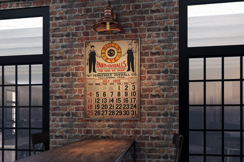 May include: A vintage poster advertising "Bulls Eye Pants & Overalls" with a calendar for July 1965. The poster is hanging on a brick wall with a copper light fixture above it.