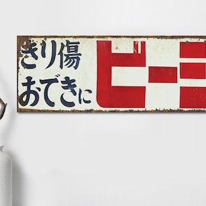 以下が含まれることがあります： 白地に赤と青の文字で書かれた、さび付いた金属製のレトロな看板。看板には日本語で「きりひろ」と、スタイリッシュな赤いフォントで「Hiro」と書かれている。