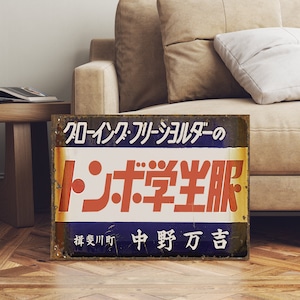 Könnte beinhalten: Ein vintage Schild aus blauem und weißem Metall mit verblasster Farbe, das für "Tonbo Student Uniforms" in Japanisch wirbt. Das Schild enthält auch den Text "Crow Ink Free Shoulder" und "Ibi River Town Nakano Manjitsu".