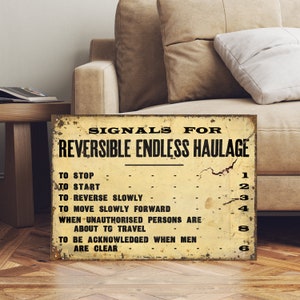 May include: A vintage-style metal sign with the text "SIGNALS FOR REVERSIBLE ENDLESS HAULAGE" and a list of signals with corresponding numbers. The sign has a yellowed background with black text and is slightly worn.