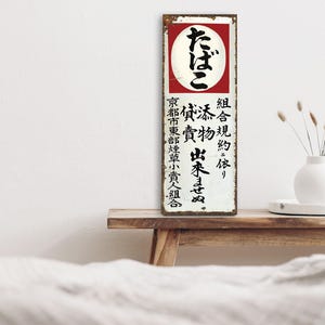 以下が含まれることがあります： 組合規約依り たばこ出来そめ。 京都市東部煙草小責人組合 と書かれた、ビンテージな金属製の看板。看板は白地に黒文字で、右上に赤い丸の中に黒文字で書かれた文字があります。