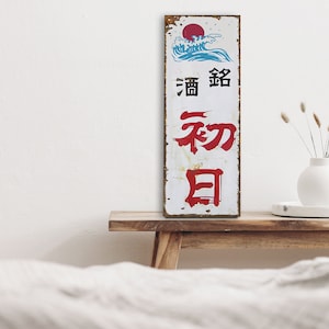Könnte beinhalten: Ein vintage, rostiges Metallschild mit japanischen Schriftzeichen und einem blauen und weißen Bild einer Welle und einer roten Sonne. Das Schild lautet "酒 " und "和日".