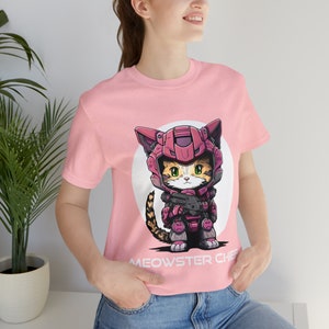 May include: Pink t-shirt with a cartoon cat wearing a pink and gray helmet and holding a gun. The text "MEOWSTER CHIEF" is printed below the cat.