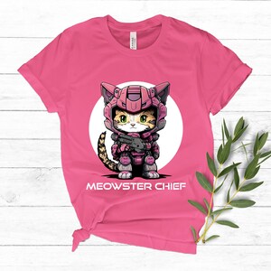 May include: Pink t-shirt with a cartoon cat wearing a pink and grey space suit and holding a gun. The cat is in a white circle with the text "MEOWSTER CHIEF" below it.