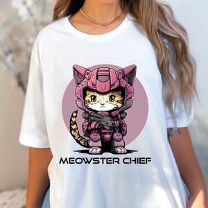 May include: White t-shirt with a pink and white cartoon cat wearing a pink and white helmet and holding a gun. The text "MEOWSTER CHIEF" is printed below the cat.