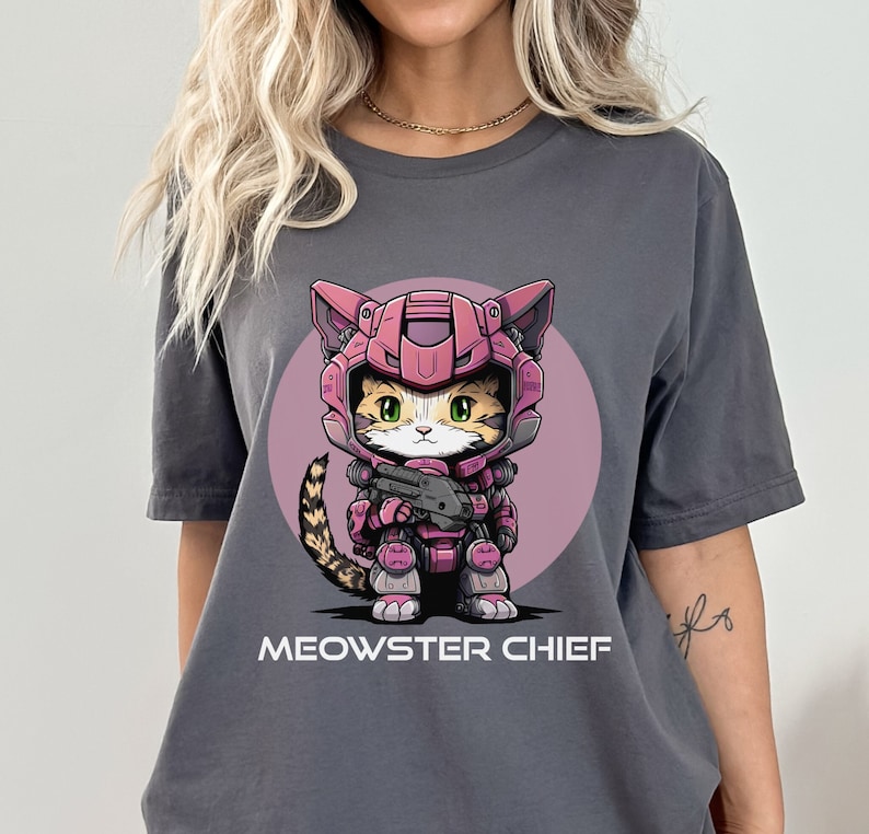 May include: A gray t-shirt with a cartoon cat wearing pink and purple armor and holding a gun. The text "MEOWSTER CHIEF" is printed below the cat.
