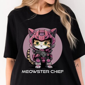 May include: Black t-shirt with a pink and gray illustration of a cat wearing a pink and gray space suit holding a gun. The text "MEOWSTER CHIEF" is printed below the illustration.