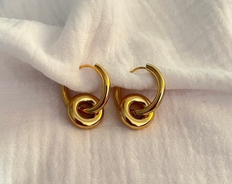 May include: Gold hoop earrings with a double circle design. The earrings are made of a smooth, shiny metal.