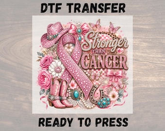 May include: A DTF transfer design featuring a pink awareness ribbon, a glittery cowboy hat, pink cowboy boots, flowers, butterflies, and a horseshoe. The text reads Stronger Than Cancer. The design includes pearls, bows, and turquoise accents.