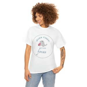 May include: White t-shirt with a blue circle graphic featuring a cartoon seal holding a pink cake and the text "¡BUEN FINDE! MOTHER focas"