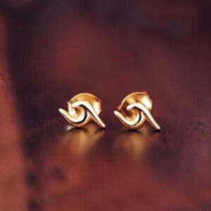 Puede incluir: Un par de pendientes de botón de oro en forma de ola.