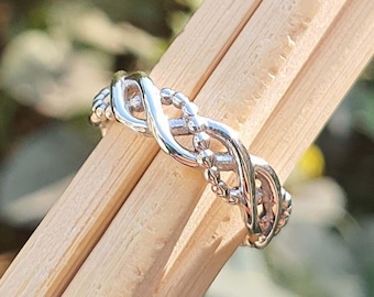 May include: A silver ring with a braided design. The ring is made of a smooth metal and has a polished finish.