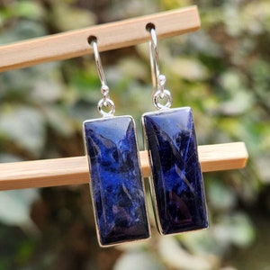 Op de afbeelding: Een paar zilveren oorhangers met rechthoekige blauwe edelsteen druppels. De edelstenen hebben een marmerpatroon.