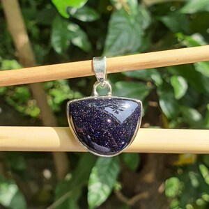 May include: A silver pendant featuring a dark blue, sparkly, semi-precious stone set in a half-moon shape.