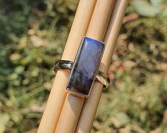 May include: A silver ring with a rectangular, dark blue labradorite gemstone.