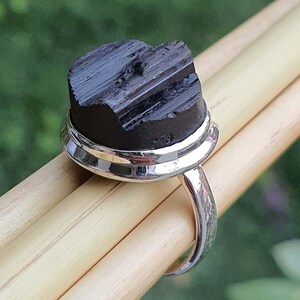 Op de afbeelding: Een zilveren ring met een zwarte toermalijn edelsteen. De ring is gezet in een zilveren band met een dubbele bezel.