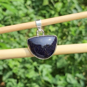 May include: A silver pendant with a dark blue, sparkly, semi-circular stone.