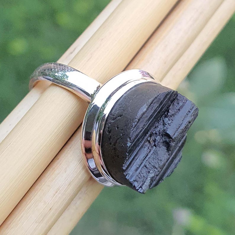 Op de afbeelding: Een zilveren ring met een zwarte, gestreepte steen gezet in een bezel setting. De steen is een natuurlijke, ruw geslepen, zwarte edelsteen.