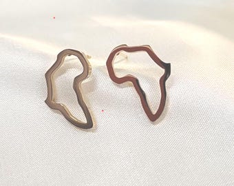 May include: A pair of gold-colored earrings shaped like the outline of the continent of Africa.