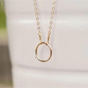 Puede incluir: Un collar de cadena de oro con un colgante circular simple.