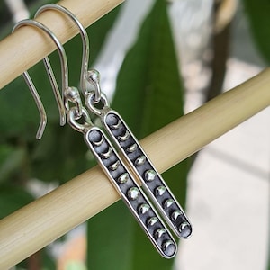 Può includere: Orecchini pendenti in argento con un design di luna crescente in varie fasi. Gli orecchini sono lunghi circa 3,8 cm.