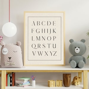 May include: A white shelf with a wooden frame, a gray teddy bear, a light brown plush toy with a bow tie, and a framed print with the alphabet in black text on a white background.