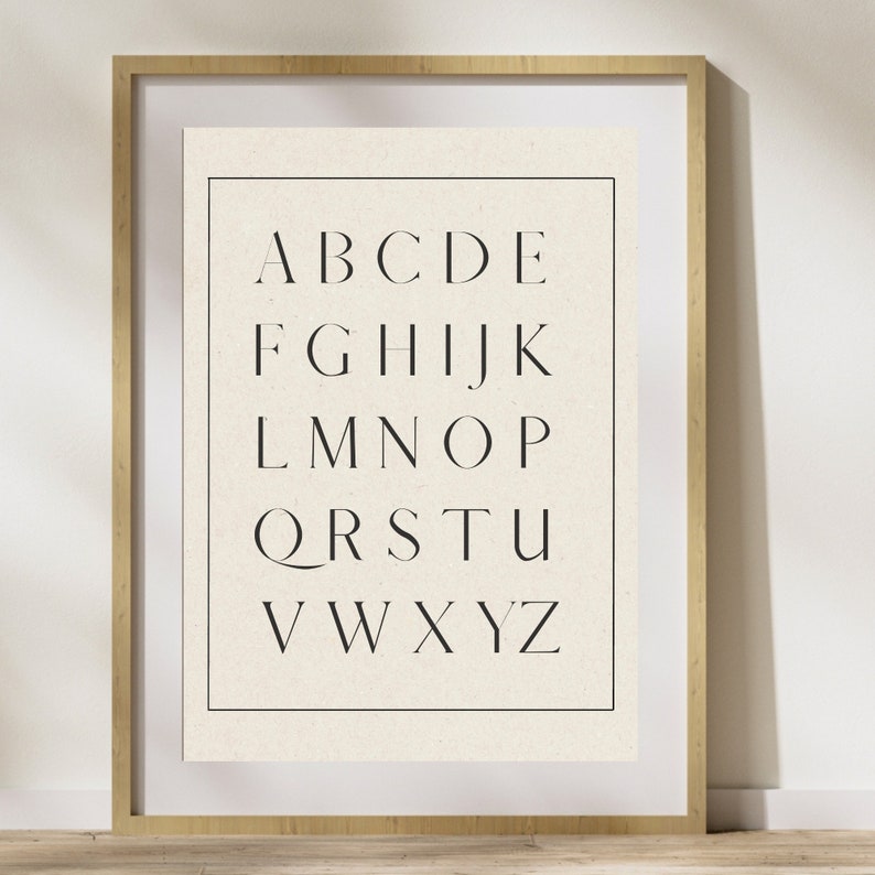May include: A framed print with a white background and black text. The text is the alphabet in uppercase letters, arranged in five rows. The letters are in a simple, modern font.