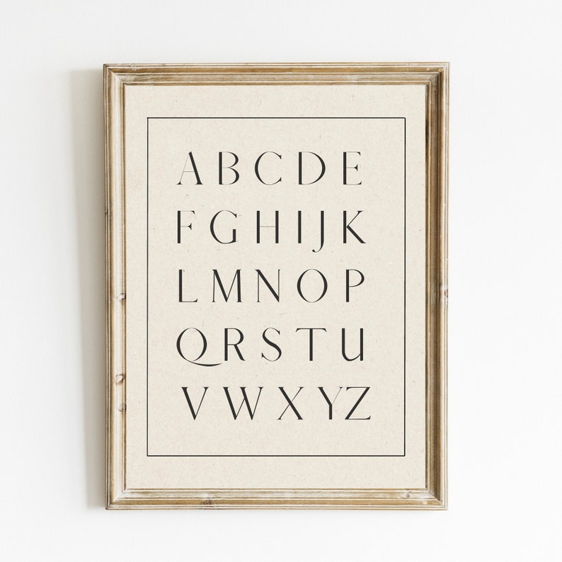 May include: A framed print of the alphabet in a simple, modern font. The letters are printed in black on a cream-colored background.