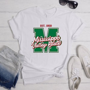 May include: White t-shirt with a green and red Mississippi Valley State logo. The logo features a large "M" with the words "Mississippi Valley State" in a red script font. The text "EST. 1950" is above the logo.