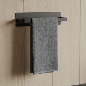 Może przedstawiać: Matowy, czarny wieszak na ręczniki zamontowany na jasnej ścianie z drewnianych paneli. Szary ręcznik jest schludnie zawieszony na wieszaku. Ręcznik ma teksturowany wygląd i kontrastującą szarą obwódkę. Całość jest nowoczesna i minimalistyczna.
