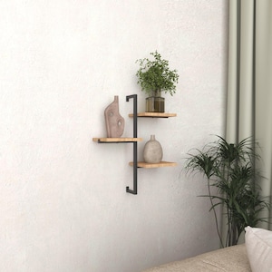 May include: A set of three wooden shelves with black metal supports. The shelves are mounted on a white wall and feature decorative items, including a plant, a vase, and a sculpture.