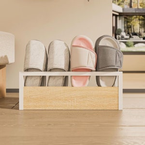 Puede incluir: Un zapatero blanco y con aspecto de madera que contiene cuatro pares de zapatillas. Dos pares son de color gris claro, uno es rosa y blanco, y el &uacute;ltimo es gris y blanco. El zapatero est&aacute; sobre un suelo de madera clara.