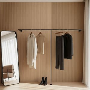 May include: A minimalist clothing rack with a full-length mirror. The rack displays a white long shirt, a tan sleeveless top, gray pleated pants, and a black blazer. Black ankle boots are on the floor. The background is a light wood-paneled wall.