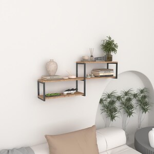 May include: A set of two floating shelves with a black metal frame and a light brown wood finish. The shelves are mounted on a white wall and are decorated with books, a vase, and other decorative items.