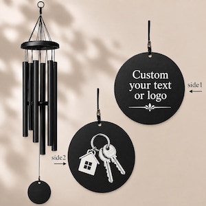 Peut inclure: Un carillon à vent noir avec un sommet circulaire, plusieurs tubes cylindriques et un capteur de vent rond. Deux disques noirs circulaires supplémentaires sont présentés : le côté 1 affiche le texte "Custom your text or logo" et le côté 2 montre une icône de maison et de clés.