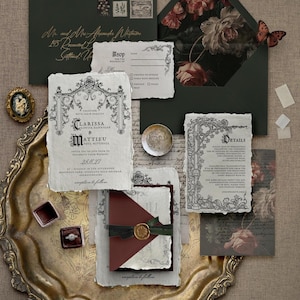 May include: An elegant wedding invitation suite featuring a dark green envelope with gold calligraphy, floral-lined envelope, and ornate invitation cards. Includes a gold-toned tray, ring boxes, and a decorative butterfly.