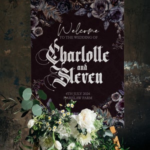 Op de afbeelding: Een welkomstbord voor een bruiloft op een ezel. Het bord is donker bordeauxrood met bloemaccenten en de namen "Charlotte en Steven" in elegant schrift. Een bloemstuk van witte bloemen en groen siert de basis.
