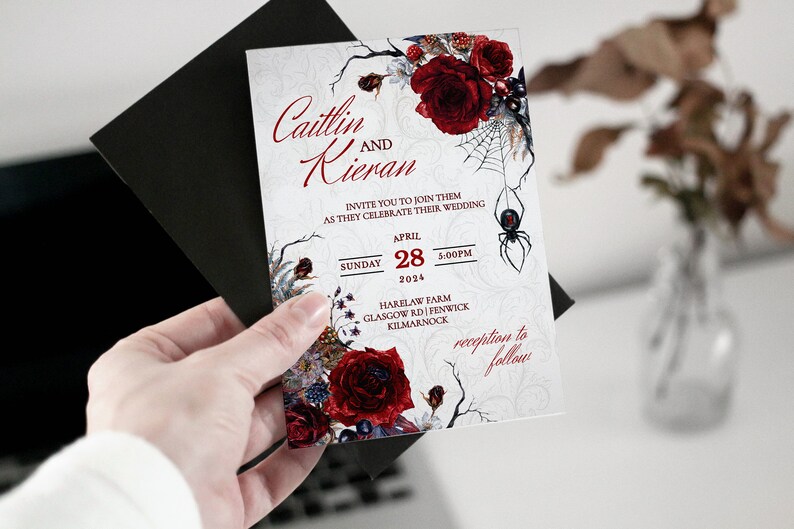 Op de afbeelding: Huwelijksuitnodiging met een gotische uitstraling. De uitnodiging toont een zwarte spin, rode rozen en de tekst "Caitlin en Kieran" met de datum "28 april 2024" en de tijd "17:00 uur".
