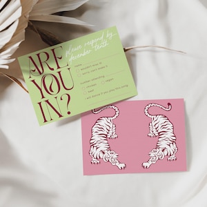 May include: Two cards on a white surface. One is light green with the text "ARE YOU IN?" in burgundy. The other is pink with two white tiger illustrations. The green card has fill-in-the-blank options.