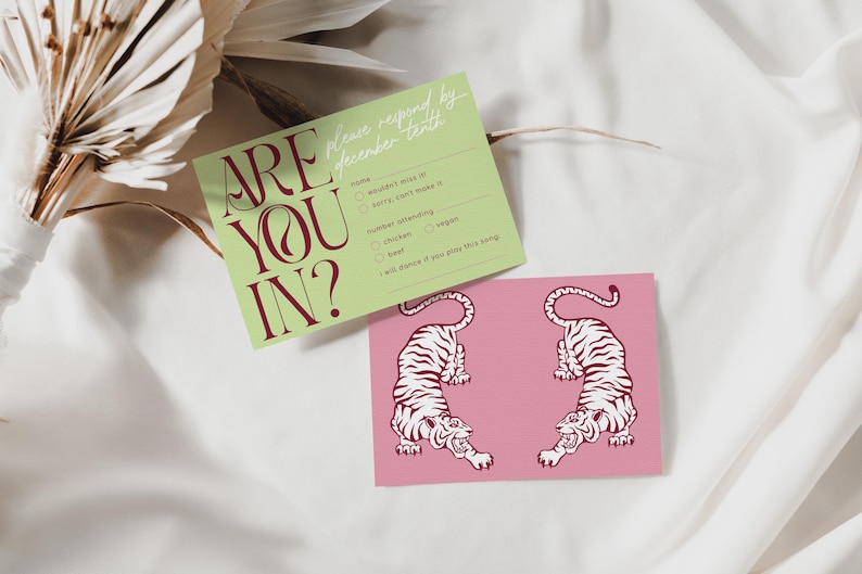 May include: Two cards on a white surface. One is light green with the text "ARE YOU IN?" in burgundy. The other is pink with two white tiger illustrations. The green card has fill-in-the-blank options.