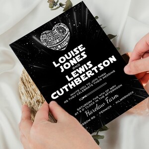 May include: Black and white wedding invitation with a Star Wars theme. The invitation features a Death Star in the shape of a heart with the text "Louise Jones and Lewis Cuthbertson invite you to join them as they celebrate their wedding. Saturday the 4th of May at 3 o'clock in the afternoon. Harelaw Farm. Fenwick. Kilmarnock."