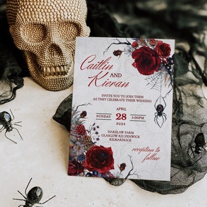 Op de afbeelding: Een huwelijksuitnodiging met een gotische uitstraling. De uitnodiging heeft een donkerrood bloemmotief met een spinnenweb en een zwarte spin. De tekst luidt "Caitlin en Kieran" en bevat de datum en tijd van de bruiloft. De bruiloft zal plaatsvinden op Harelaw Farm in Kilmarnock, Schotland.