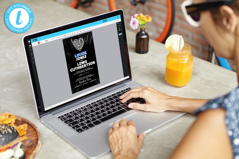May include: A laptop computer displaying a wedding invitation template with a black and blue design. The invitation reads "Louise Jones and Lewis Cuthbertson".