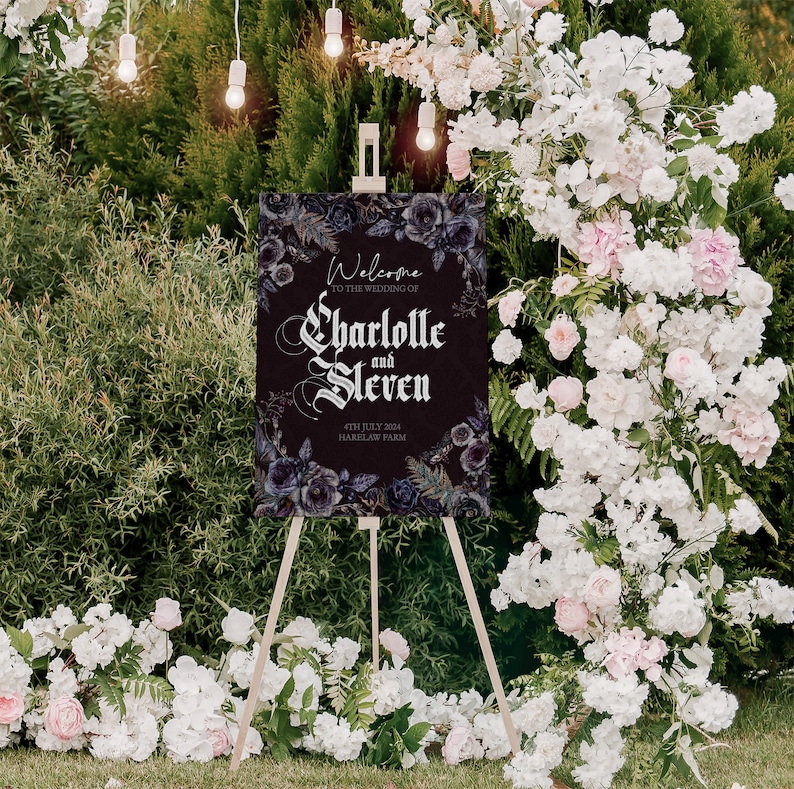 May include: A black wedding welcome sign with a dark floral design and the text "Welcome to the wedding of Charlotte and Steven 4th July 2024 Harklaw Farm".