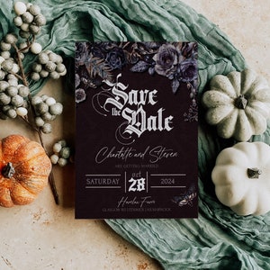 Op de afbeelding: Een bordeauxrode Save the Date kaart met bloemaccenten en de namen Charlotte en Steven. De kaart is omgeven door pompoenen, bessen en een saliegroene stof. De datum is 28 oktober 2024.