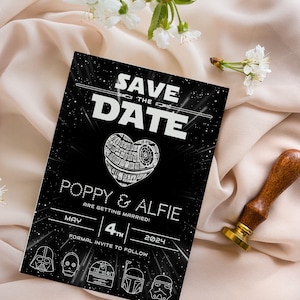 Pu&ograve; includere: Carta salva la data in bianco e nero con tema Star Wars. La carta presenta un cuore a forma di Morte Nera con il testo "Save the Date" e "Poppy & Alfie si sposano!" La data &egrave; il 4 maggio 2024. La carta presenta anche una fila di personaggi di Star Wars in basso.