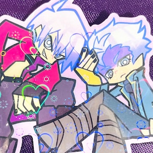 May include: A holographic sticker featuring two anime-style characters. One character is in a pink and black outfit with white hair, and the other is in a blue jacket with purple hair. The sticker has heart and circle accents.