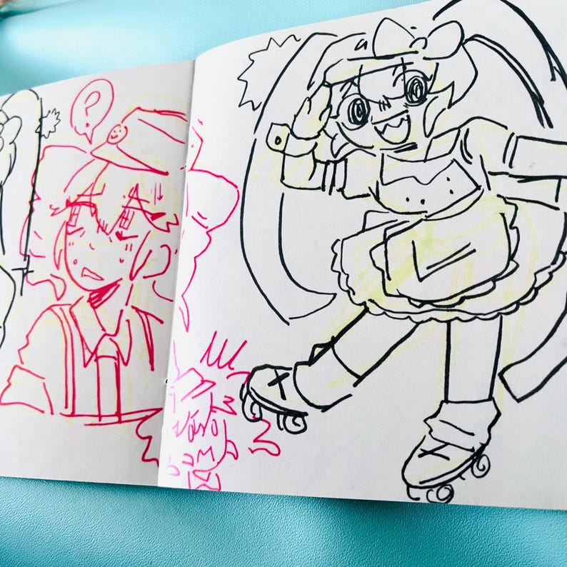 May include: A sketchbook with cartoon illustrations. One drawing features a person in a uniform with a question mark above their head. The other drawing shows a character on roller skates, wearing a dress and a bow.